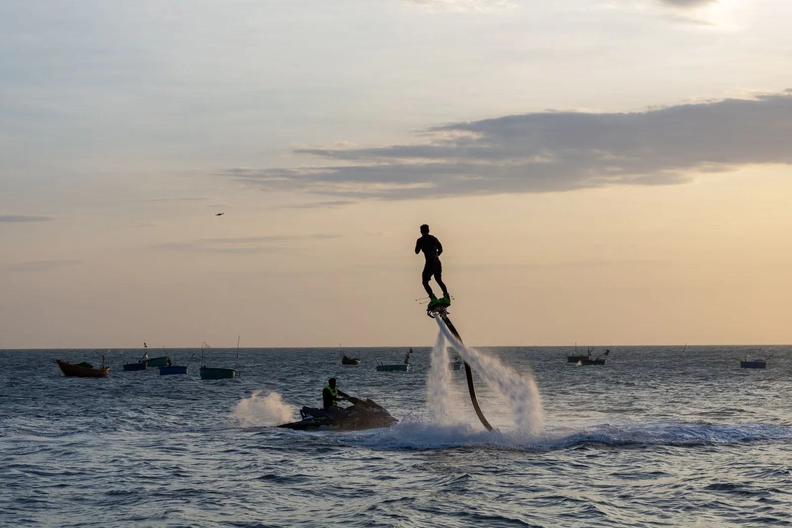 Un pratiquant de flyboard au-dessus de l’eau avec une motomarine à proximité