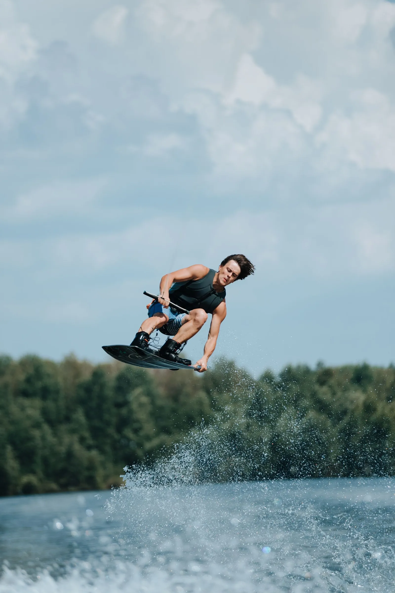 Un wakeboardeur en l’air tient son palonnier au-dessus d’un lac